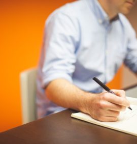 LearnOnline Self-study Business Studies A level - Orange background with someone sat at desk writing