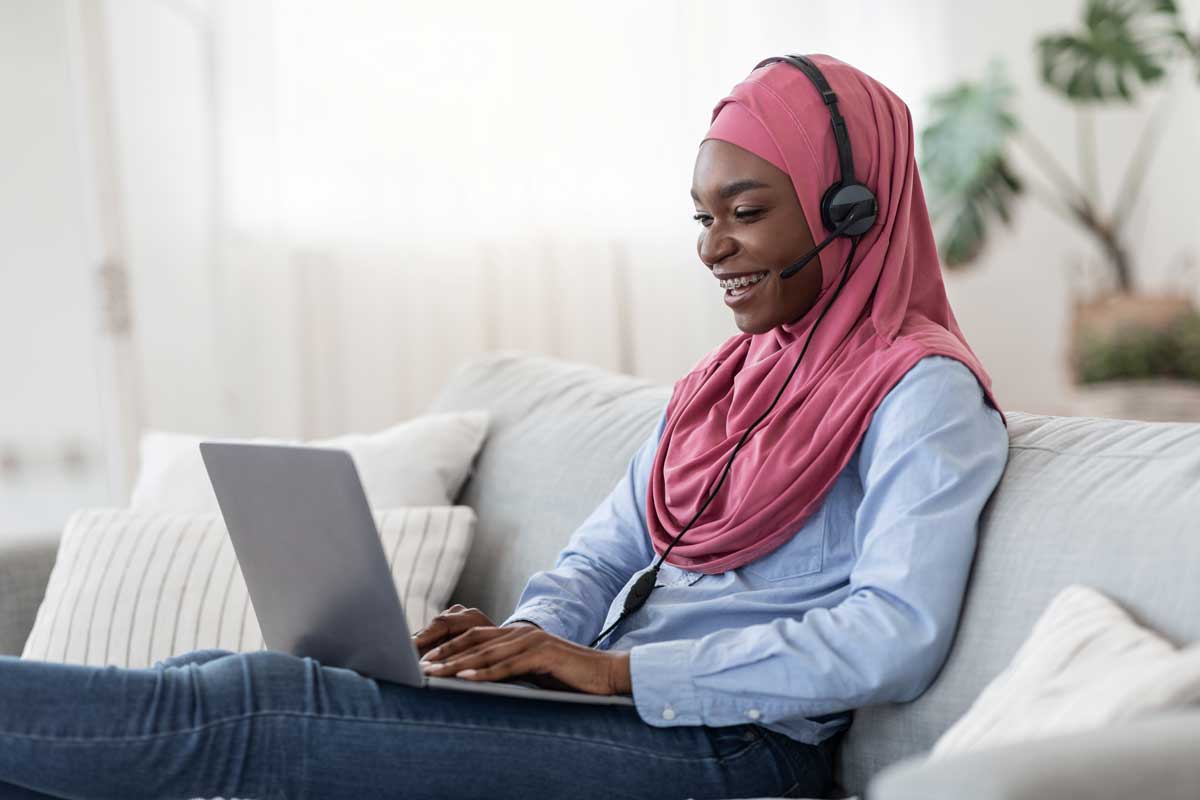 A-levels-2021 person smiling wearing a headset looking at a laptop