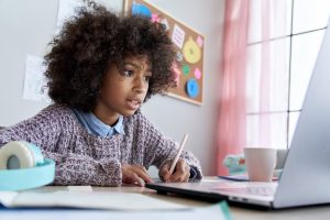 Choose your IGCSEs Choose your IGCSEs - 14-16 year old sat at desk writing in front of laptop
