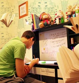 LearnOnline Exams - 16-18 year old sat at desk with writing on wall and books flying around