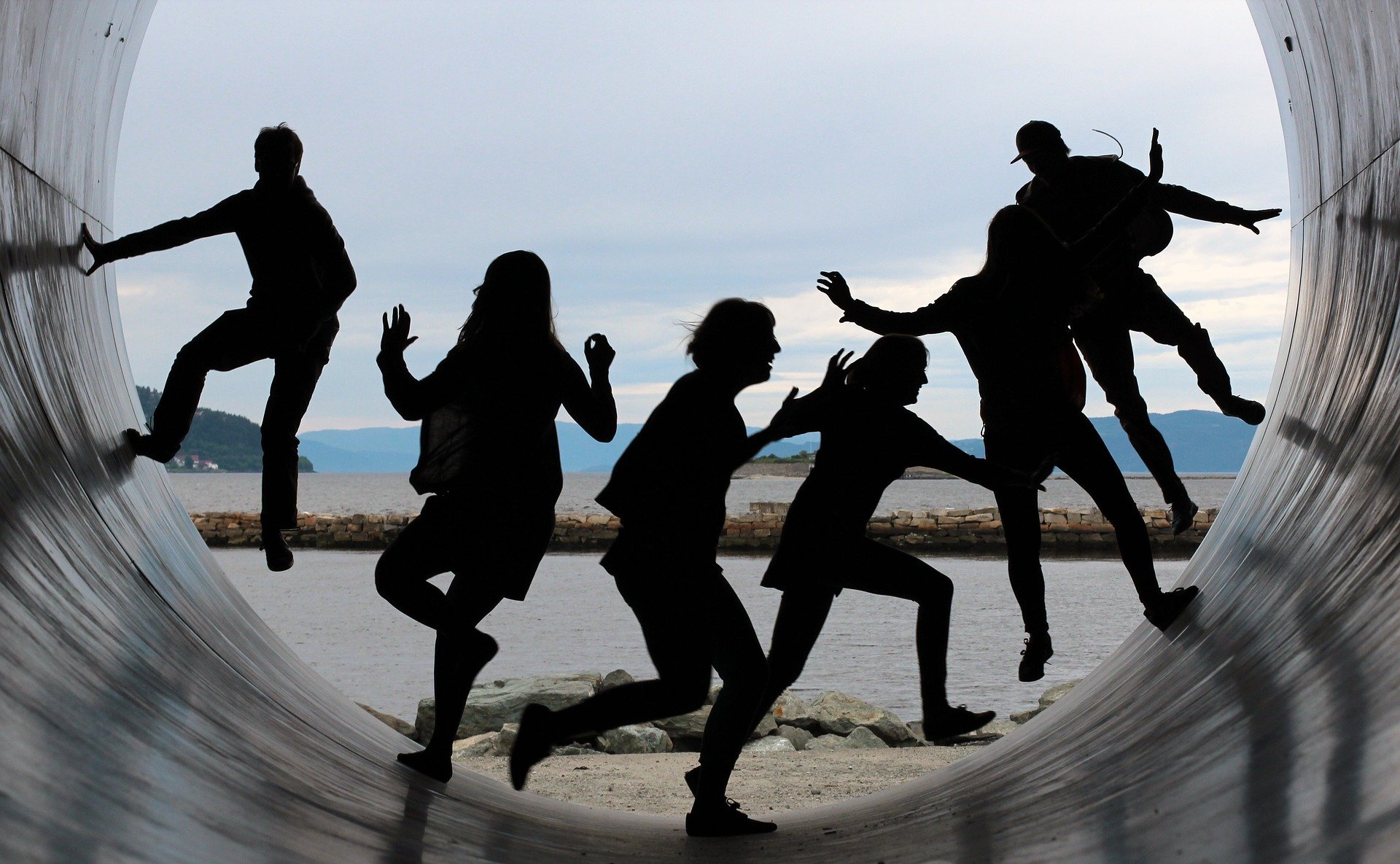 Meet the Team Meet the Team. Silhouettes of adults running on a large concrete tube or half pipe with water in background