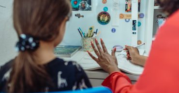 LearnOnline News Article - can I teach my child IGCSEs at home? Adult and child sat in kitchen studying