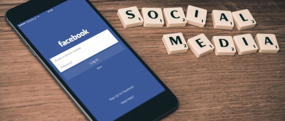 Social Media news article Mobile phone with Facebook icon on the screen with Scrabble letters spelling out 'social media'