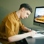 LearnOnline A-level Packages 16-18 year old boy at desk with computer, writing in notebook
