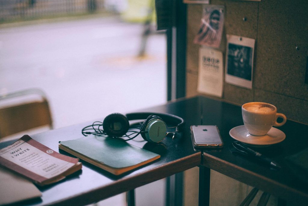The Arts Package: table with headphones, book, phone and cup of coffee