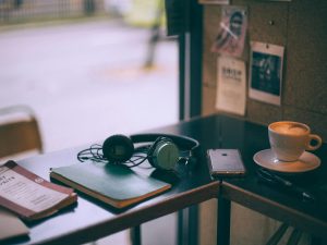 The Arts Package: table with headphones, book, phone and cup of coffee